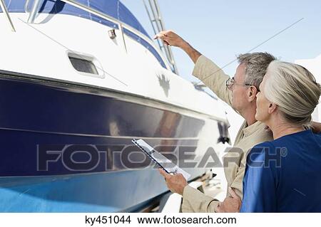 Couple standing near a yacht with a brochure View Large Photo Image Picture - Couple standing near a yacht with a brochure. Fotosearch