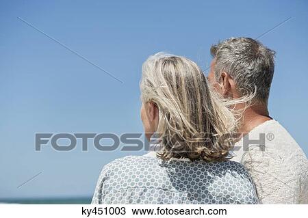 Stock Image - Couple standing on the beach. Fotosearch