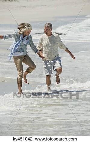 Stock Image - Couple walking on the beach. Fotosearch
