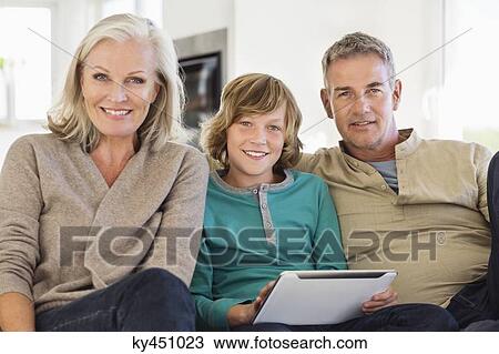 Portrait of a boy holding a digital tablet sitting with his grandparents View Large Photo Image Stock Image - Portrait of a boy holding a digital tablet sitting with his grandparents. Fotosearch