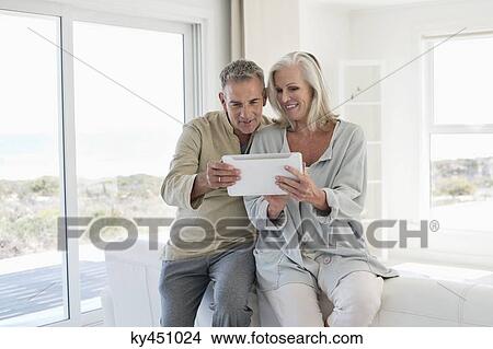 Smiling senior couple using a digital tablet View Large Photo Image Picture - Smiling senior couple using a digital tablet. Fotosearch