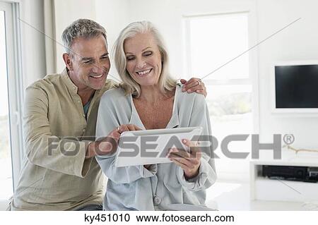 Stock Image - Smiling senior couple using a digital tablet. Fotosearch