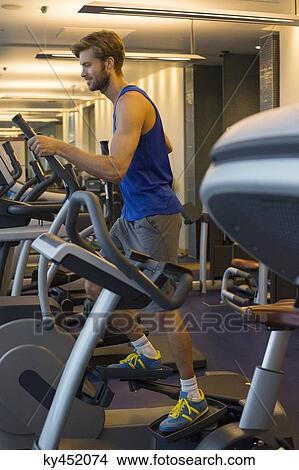 Man exercising on a machine in a gym View Large Photo Image Picture - Man exercising on a machine in a gym. Fotosearch