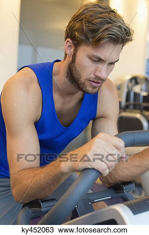 Man exercising on a machine in a gym View Large Photo Image Stock Image - Man exercising on a machine in a gym. Fotosearch