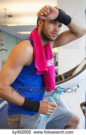 Man holding a water bottle in a gym View Large Photo Image Stock Image - Man holding a water bottle in a gym. Fotosearch