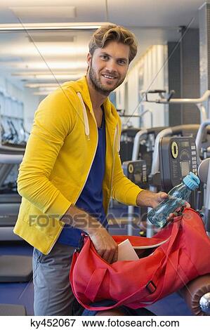 Man packing his bag in a gym after workout View Large Photo Image Stock Photo - Man packing his bag in a gym after workout. Fotosearch