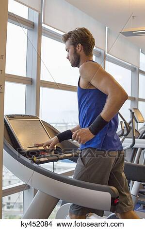Man running on a treadmill in a gym View Large Photo Image Picture - Man running on a treadmill in a gym. Fotosearch