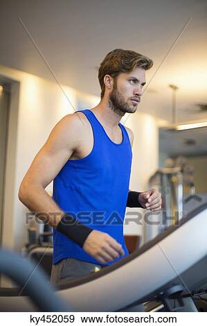Man running on a treadmill in a gym View Large Photo Image Stock Photo - Man running on a treadmill in a gym. Fotosearch