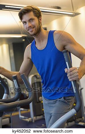 Portrait of a smiling man exercising in a gym View Large Photo Image Stock Image - Portrait of a smiling man exercising in a gym. Fotosearch