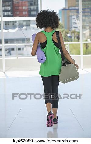 Rear view of a woman carrying an exercise mat and a bag View Large Photo Image Stock Photo - Rear view of a woman carrying an exercise mat and a bag. Fotosearch