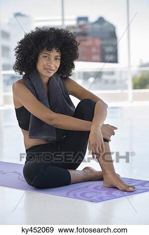 Stock Photo - Smiling woman sitting on an exercise mat. Fotosearch