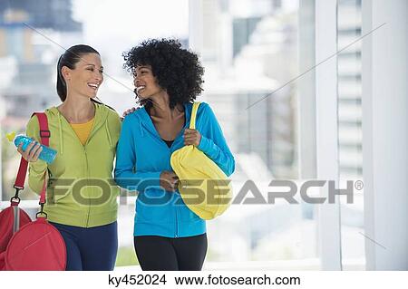 Picture - Two happy female friends carrying gym bags. Fotosearch