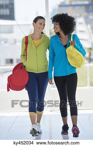 Picture - Two happy female friends carrying gym bags. Fotosearch