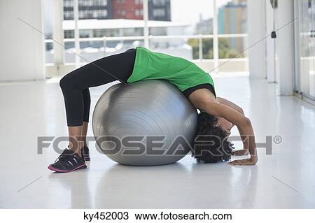Woman exercising on a fitness ball in a gym View Large Photo Image Stock Image - Woman exercising on a fitness ball in a gym. Fotosearch