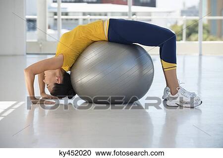 Stock Image - Woman exercising on a fitness ball in a gym. Fotosearch