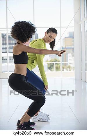 Woman exercising with her instructor in a gym View Large Photo Image Stock Image - Woman exercising with her instructor in a gym. Fotosearch