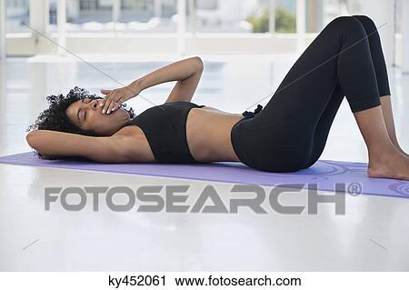 Woman lying on an exercise mat and yawning View Large Photo Image Stock Image - Woman lying on an exercise mat and yawning. Fotosearch