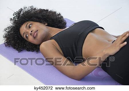 Woman lying on an exercise mat View Large Photo Image Stock Image - Woman lying on an exercise mat. Fotosearch