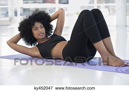 Woman practicing yoga on an exercise mat View Large Photo Image Stock Photo - Woman practicing yoga on an exercise mat. Fotosearch