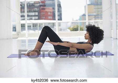 Stock Photograph - Woman practicing yoga on an exercise mat. Fotosearch