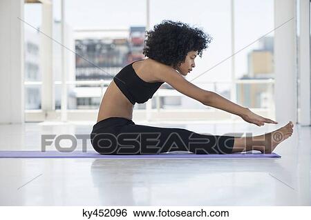 Stock Photograph - Woman practicing yoga on an exercise mat. Fotosearch