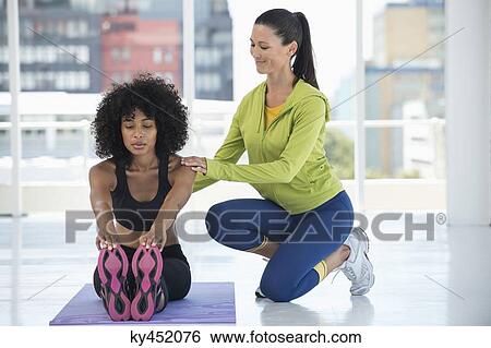 Woman practicing yoga with the help of an instructor View Large Photo Image Stock Photograph - Woman practicing yoga with the help of an instructor. Fotosearch