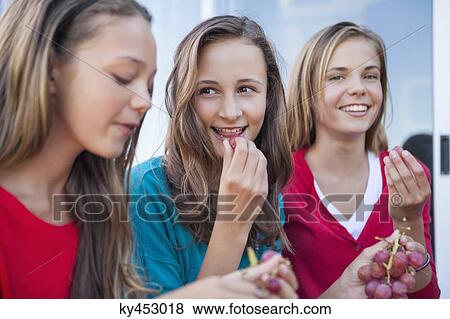 Stock Photo - Close-up of three girls eating grapes. Fotosearch