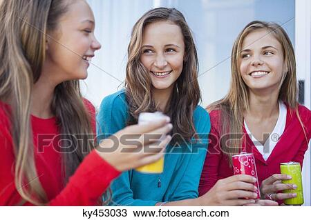 Stock Image - Close-up of three girls holding soft drink cans. Fotosearch