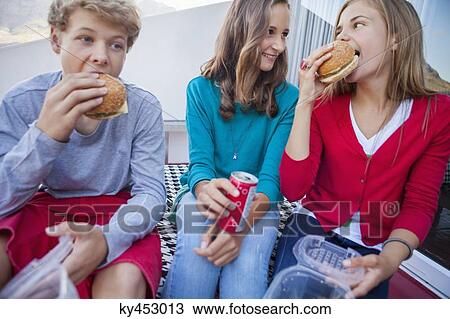 Friends enjoying fast food together View Large Photo Image Stock Image - Friends enjoying fast food together. Fotosearch