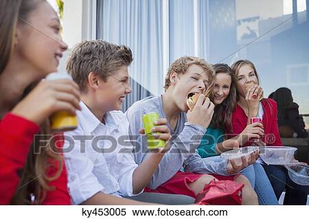 Friends enjoying fast food together View Large Photo Image Stock Photography - Friends enjoying fast food together. Fotosearch