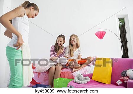 Girl trying on skirt with her friends at a slumber party View Large Photo Image Stock Photo - Girl trying on skirt with her friends at a slumber party. Fotosearch
