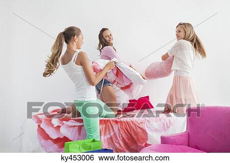 Girls having pillow fight on the bed at a slumber party View Large Photo Image Stock Photograph - Girls having pillow fight on the bed at a slumber party. Fotosearch