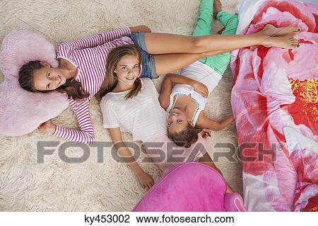 Three girls lying on a carpet at a slumber party View Large Photo Image Stock Image - Three girls lying on a carpet at a slumber party. Fotosearch
