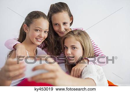 Three girls taking a picture of themselves with a mobile phone at a slumber party View Large Photo Image Stock Photo - Three girls taking a picture of themselves with a mobile phone at a slumber party. Fotosearch