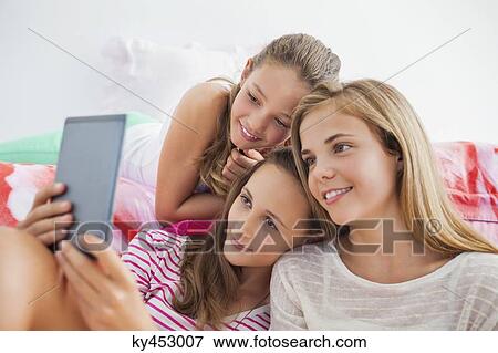 Three girls using a digital tablet at a slumber party View Large Photo Image Stock Photo - Three girls using a digital tablet at a slumber party. Fotosearch