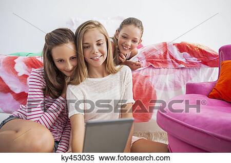 Three girls using a digital tablet at a slumber party View Large Photo Image Stock Photography - Three girls using a digital tablet at a slumber party. Fotosearch