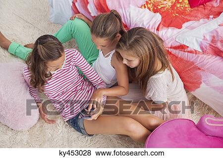 Three girls using a mobile phone at a slumber party View Large Photo Image Stock Photo - Three girls using a mobile phone at a slumber party. Fotosearch
