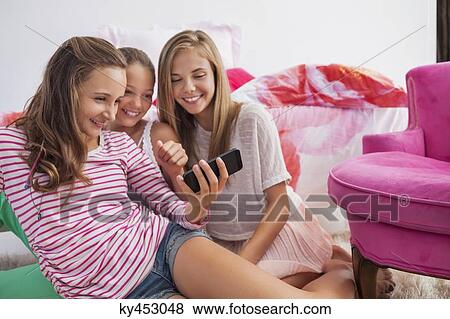 Three girls using a mobile phone at a slumber party View Large Photo Image Stock Photo - Three girls using a mobile phone at a slumber party. Fotosearch