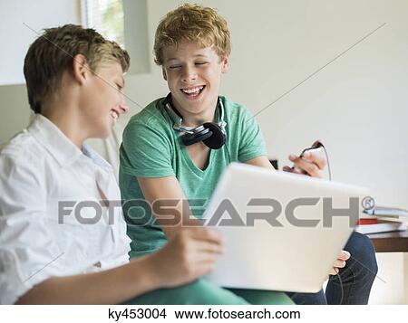 Two friends using a digital tablet View Large Photo Image Picture - Two friends using a digital tablet. Fotosearch