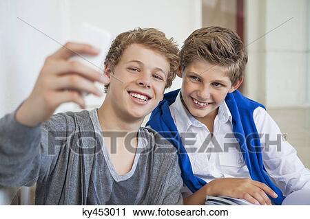 Two teenage boys taking a picture of themselves with a mobile phone View Large Photo Image Stock Image - Two teenage boys taking a picture of themselves with a mobile phone. Fotosearch