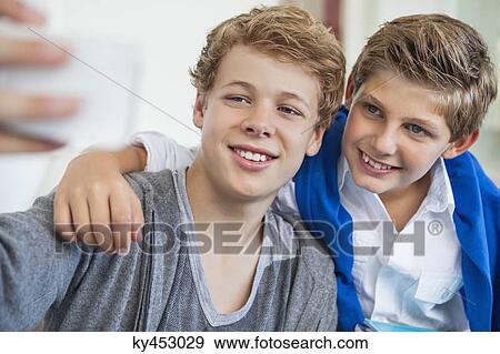 Two teenage boys taking a picture of themselves with a mobile phone View Large Photo Image Stock Photo - Two teenage boys taking a picture of themselves with a mobile phone. Fotosearch