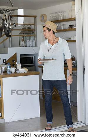 Man holding a plate of food in the kitchen View Large Photo Image Stock Image - Man holding a plate of food in the kitchen. Fotosearch