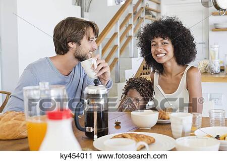 Parents with their daughter at a dining table View Large Photo Image Stock Image - Parents with their daughter at a dining table. Fotosearch
