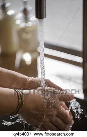 Stock Photo - Person washing hands in bathroom sink. Fotosearch