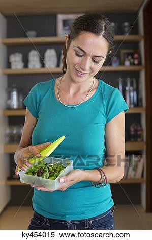 Woman holding leaf vegetables in a container and smiling at home View Large Photo Image Stock Photography - Woman holding leaf vegetables in a container and smiling at home. Fotosearch