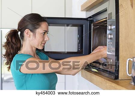 Woman putting food into a oven View Large Photo Image Stock Image - Woman putting food into a oven. Fotosearch