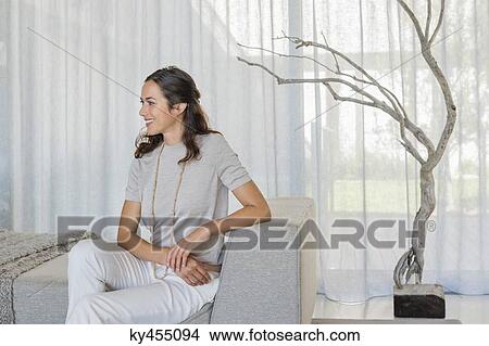 Beautiful woman sitting on a couch and smiling View Large Photo Image Picture - Beautiful woman sitting on a couch and smiling. Fotosearch