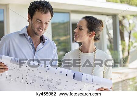 Couple holding a blueprint and smiling View Large Photo Image Stock Image - Couple holding a blueprint and smiling. Fotosearch