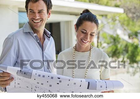 Couple holding a blueprint and smiling View Large Photo Image Stock Photo - Couple holding a blueprint and smiling. Fotosearch