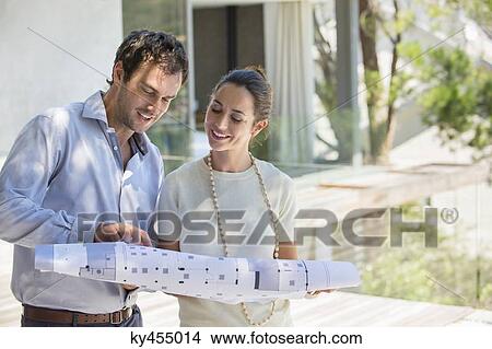 Couple looking at blueprint and smiling View Large Photo Image Picture - Couple looking at blueprint and smiling. Fotosearch